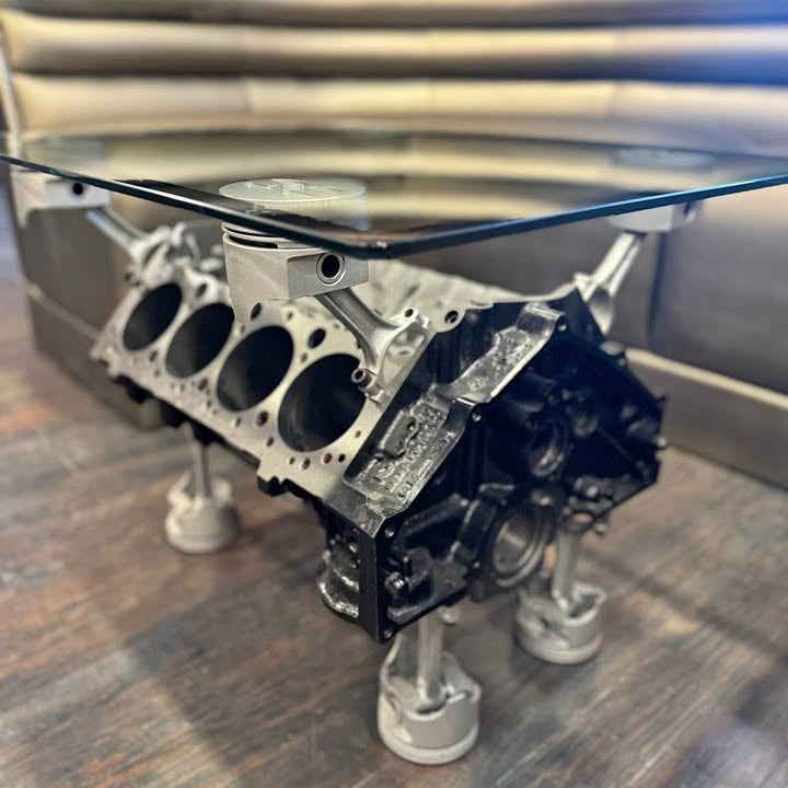 Engine block used as a glass-top table on a wooden floor.