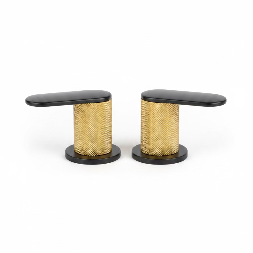 Two modern kitchen faucet handles with black tops and bases and a textured gold mesh center, shown on a speckled kitchen countertop with a blurred kitchen background.