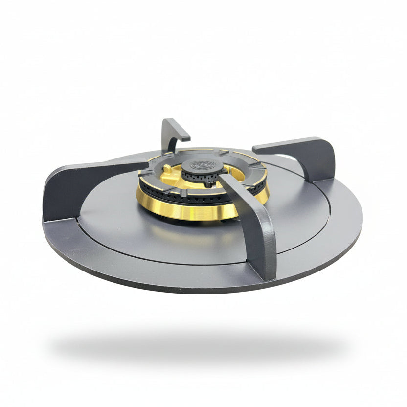 A portable folding camping gas stove with a black base, dark gray burner grates, and a gold burner head, shown on a beige carpeted floor against a white wall.