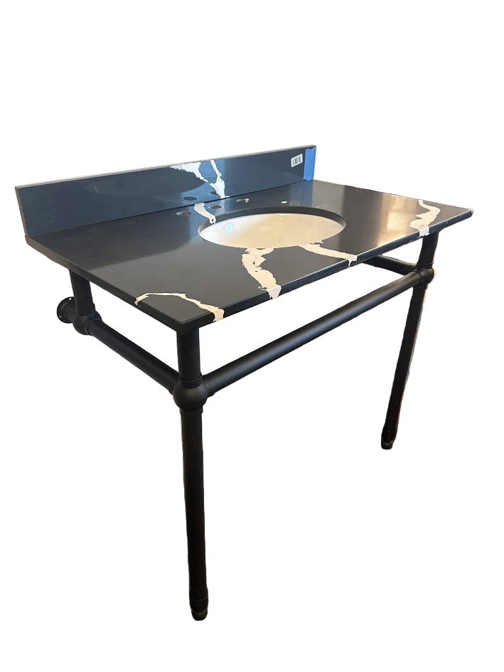 Black metal table with a glass top in a room with wooden floor and white walls.