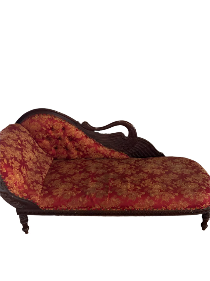 Decorative chaise lounge with red floral pattern against a plain wall with an air conditioner.
