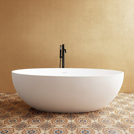 White freestanding bathtub with a black faucet against a gray wall.