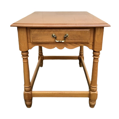 Wooden side table with a drawer in front of a white garage door