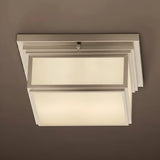 Modern ceiling light fixture with white glass shades on a brown background