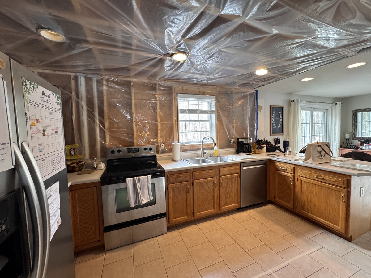 Before: original Goffstown kitchen layout with oak cabinetry and tile floor, walls opened for construction