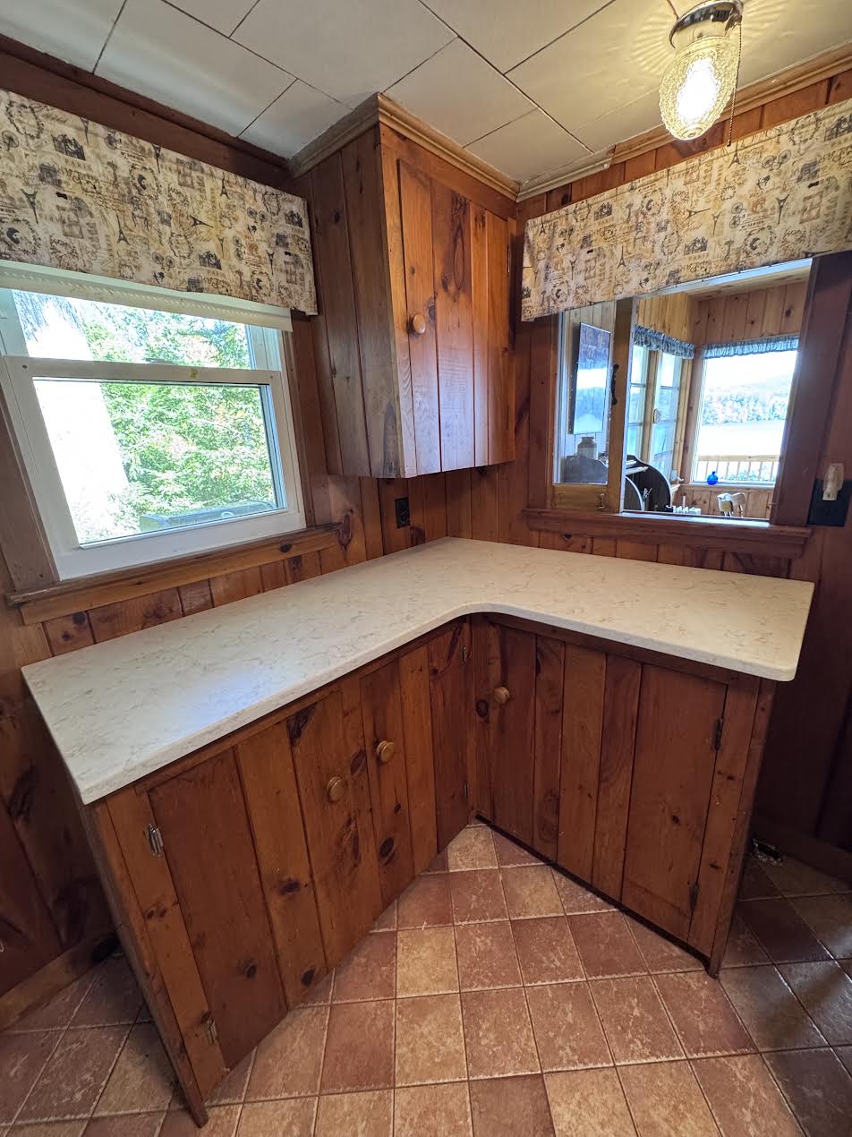 L-shaped Viatera quartz countertop on knotty pine cabinets in a lakefront cottage kitchen