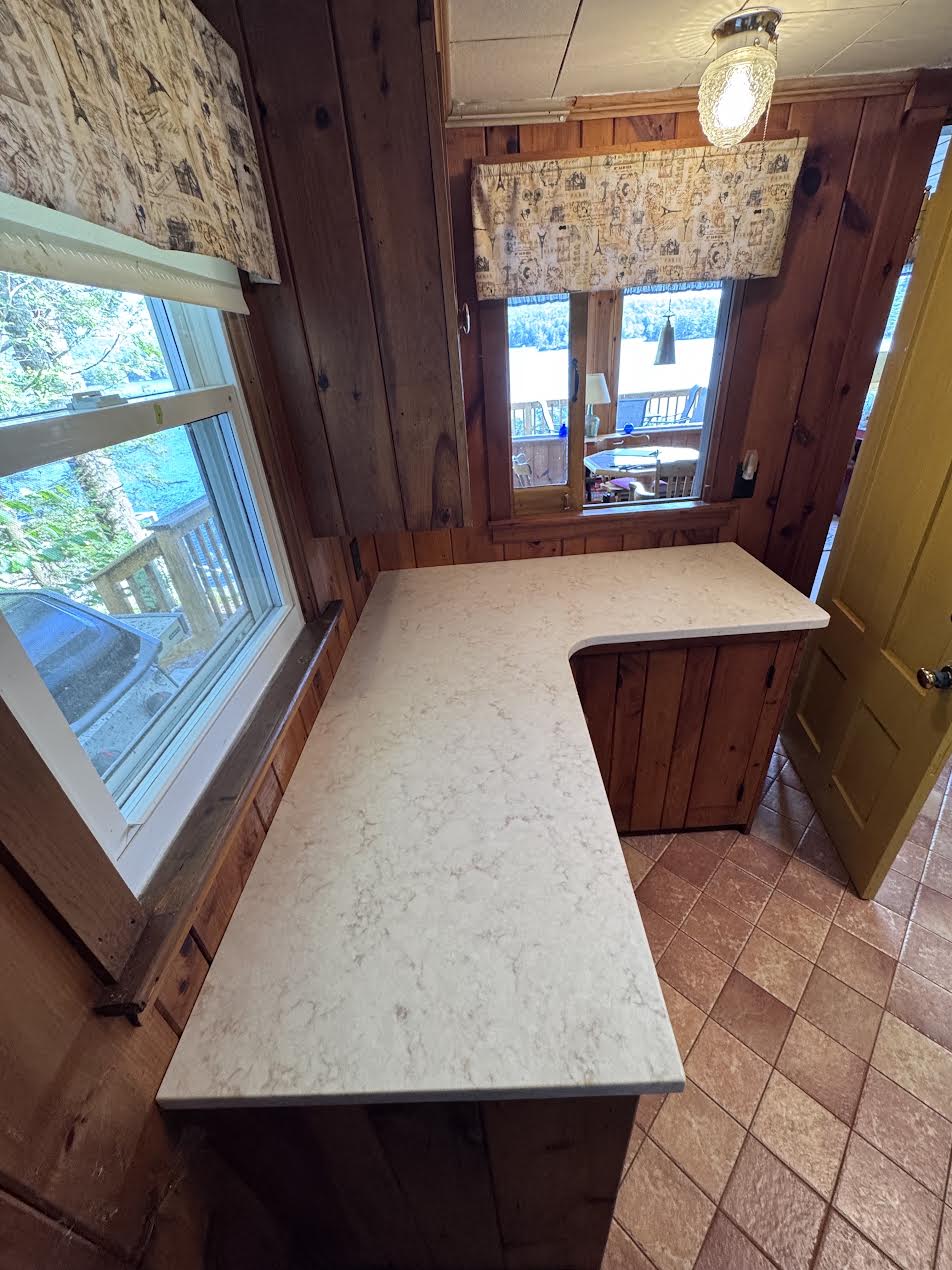 Viatera quartz L-shaped countertop by the window, lake view beyond, Stoddard NH cottage