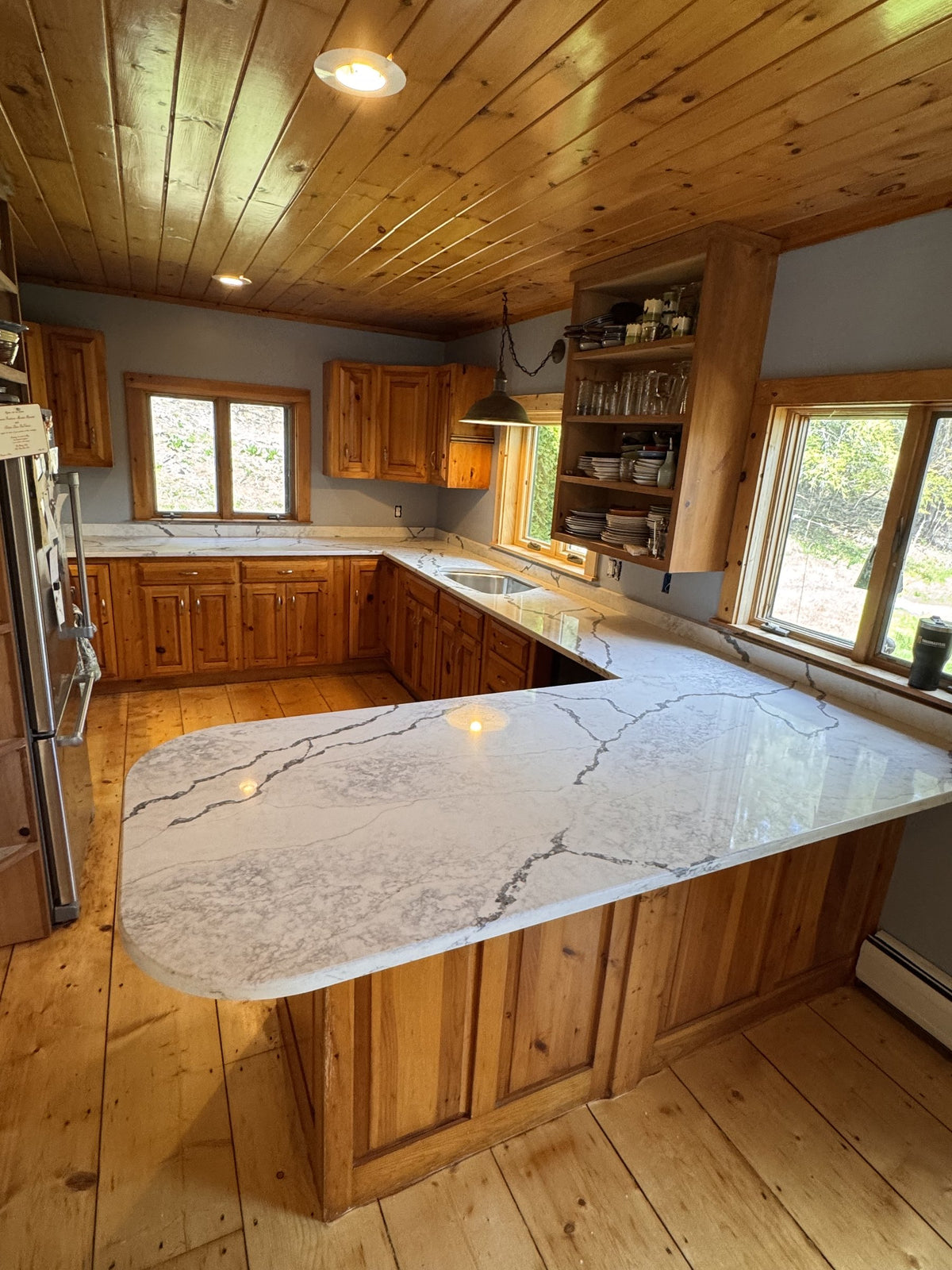After: wide view of the Vermont cottage kitchen with new quartz countertops and wood-plank ceiling